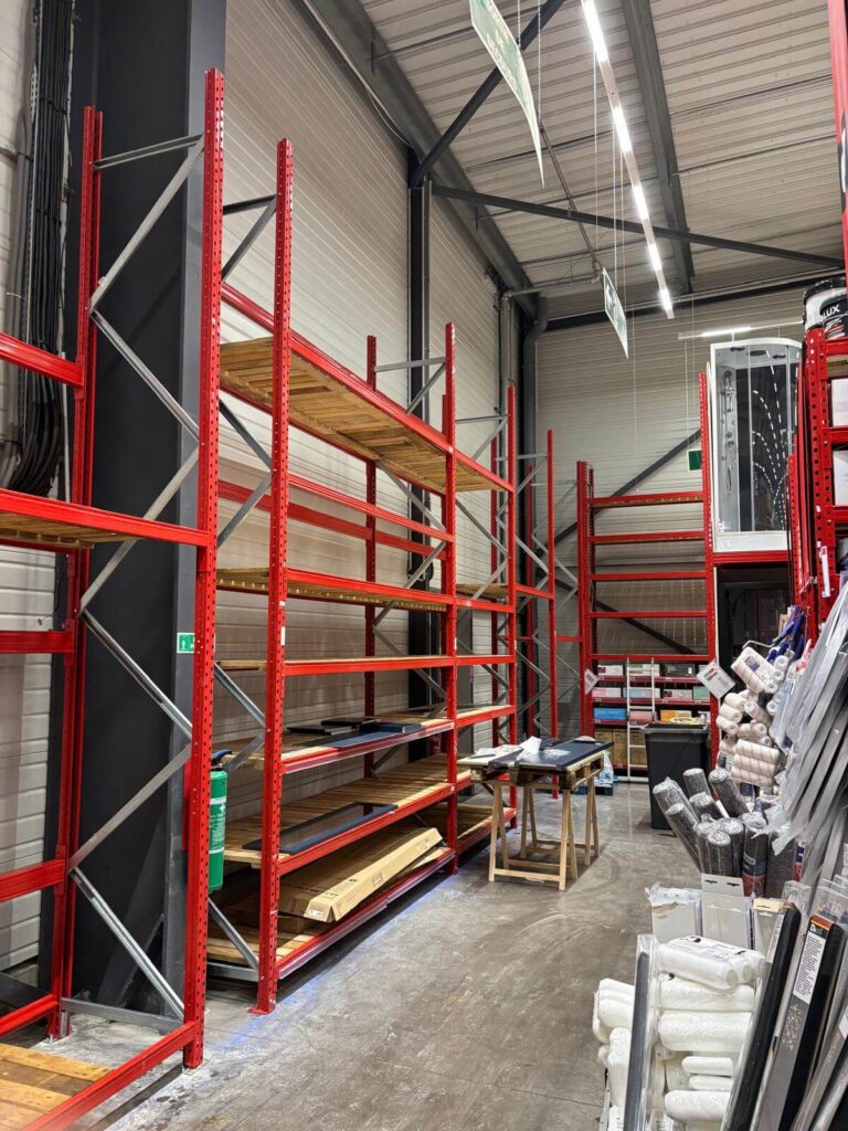 Long rayonnage rouge installé le long d’un mur avec plusieurs niveaux de plateaux